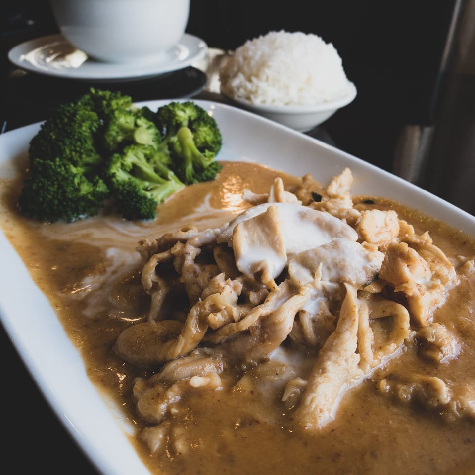 Chicken in peanut sauce with broccoli and a side of white rice and soup.
